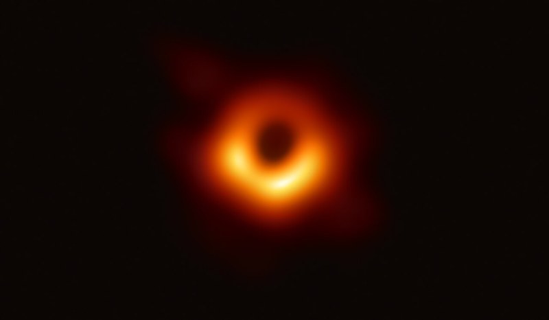 A dark circle ringed by a glowing orange crescent of light.