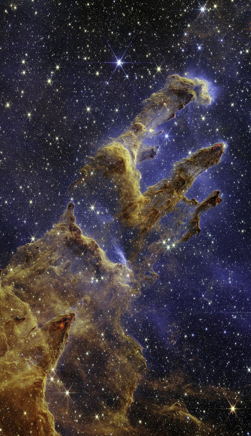 Tall columns of gas and dust glowing against a field of stars.